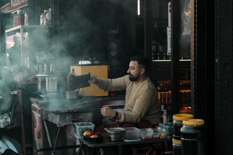 A street food vendor cooking at a stall in the evening